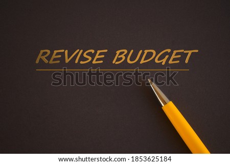REVISE BUDGET text on dark background.Orange Pen and orange text. Business concept photo showcasing Revise and edit accounting sheets from previous year
