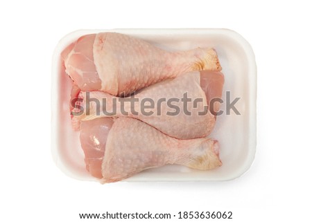 Photo of a white plastic tray, containing three chicken legs. Chicken meat in the butcher's shop.  Isolated on a white clean background. Royalty-Free Stock Photo #1853636062