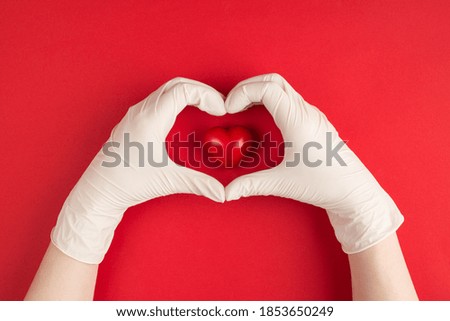 Top above overhead view photo of female hands in white gloves making heart shape and red heart in center isolated on red background