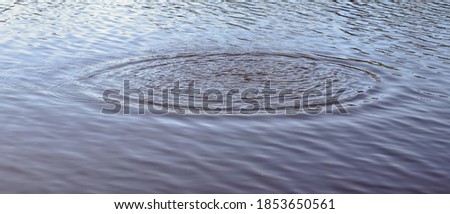 Beautiful water at a lake with splashing water and ripples on the surface with clouds and sky reflections