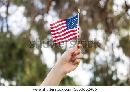 A hand waving an American fly outdoors