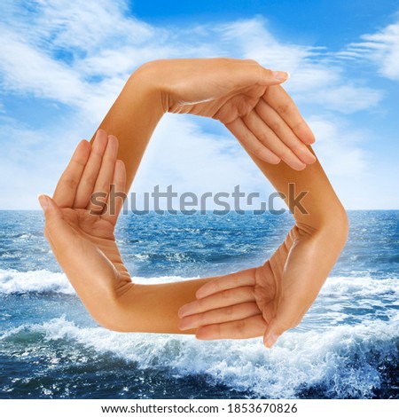 Conceptual recycling symbol made from hands over blue sea background photo-illustration. Ecology, environment, ecosystem, recycling concept.