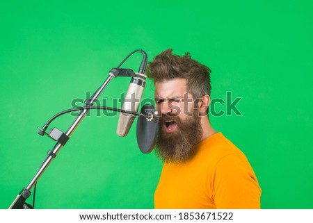 Bearded man sing in microphone. Karaoke. Man singing with a microphone. Singing in studio. Microphone. Sings a song. Studio.