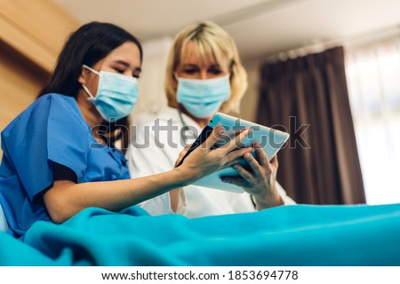 Senior woman doctor wearing protective mask with stethoscope service help support discussing and consulting talk to sick woman patient about checkup result information with tablet in hospital