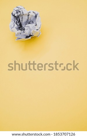 A high angle shot of a wrapped paper ball isolated on a yellow background