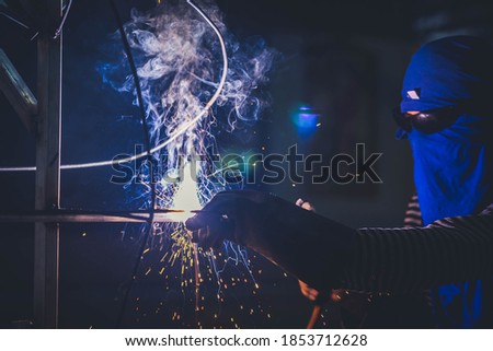 Arcing welding iron concept. Shielded metal arc welding is a fabrication or sculptural process that joins materials iron structure building on dark black background. Flame and smog from this process.