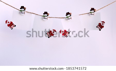 Christmas decorations against white background. small wooden snowmans and wooden santa claus with blank paper.