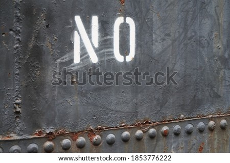 A painted NO sign on a metal wall