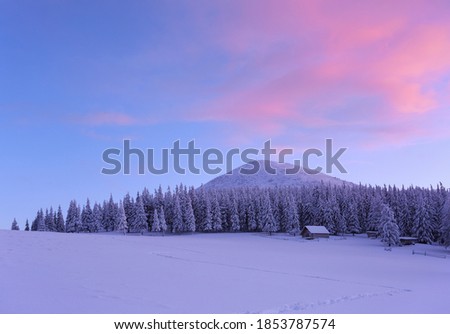 Amazing winter scenery. Old wooden hut on the lawn covered with snow. Fantastic sunrise. Landscape of high mountains and forests. Wallpaper background. Location place Carpathian, Ukraine, Europe.