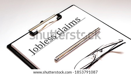 JOBLESS CLAIMS text written on paper with pen and glasses
