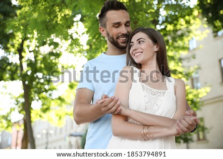Lovely young couple dancing together in park on sunny day