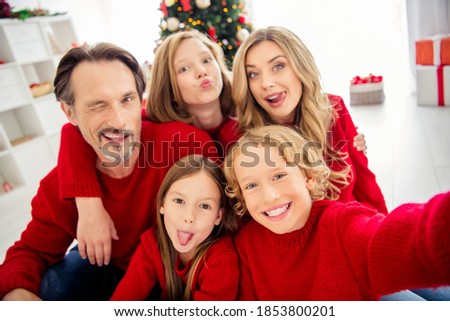 Closeup photo of full big family five people meeting three little kids cuddle tongue-out blink eye send air kiss wear red jumper in decorated living room x-mas tree garland indoors