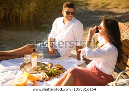 Woman taking picture of boyfriend on pier at picnic