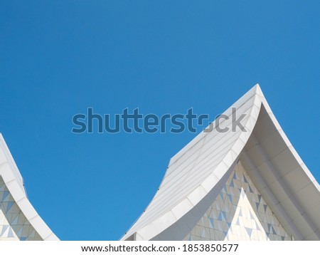 White Thai style roof design in a more modern and minimal style with clear blue sky.