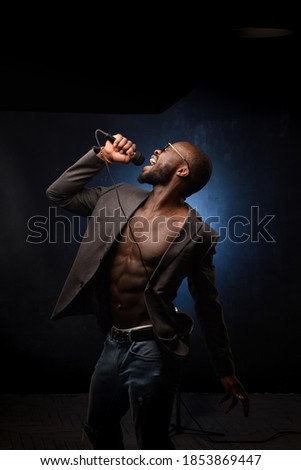 A black African American is emotionally singing into a microphone. Close-up studio portrait.