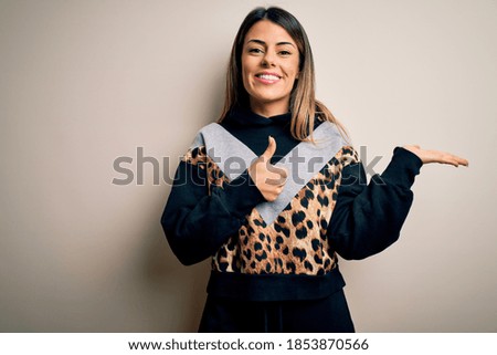 Young beautiful woman wearing casual sweatshirt standing over isolated white background Showing palm hand and doing ok gesture with thumbs up, smiling happy and cheerful