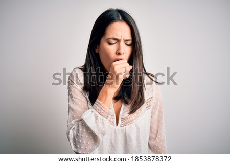 Young brunette woman with blue eyes wearing casual t-shirt over isolated white background feeling unwell and coughing as symptom for cold or bronchitis. Health care concept.