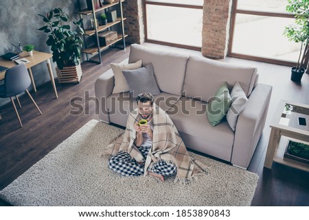 High angle above view photo of handsome guy homey sit comfy floor sofa quarantine stay home eyes closed drink hot tea beverage covered blanket pajama pants t-shirt living room indoors