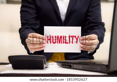 the word humility is written on a white notebook held by a businesswoman. religion and education concept. 