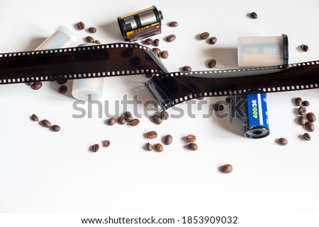 Coffee beans, two film rolls, canisters and a 35mm filmstrip in a white bakground 