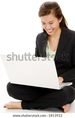 A pretty young asian businesswoman using a laptop computer whilst sitting on the floor