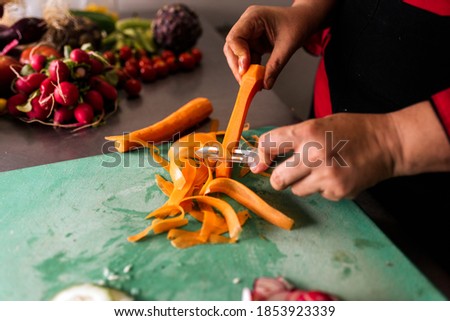 Stock photo of unrecognized chef working in the kitchen peeling carrots.