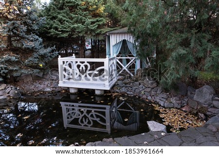 Beautiful white gazebo for photographing the bride and groom in the autumn park.