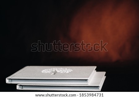 Composition of photo books in natural white leather of different sizes. The white paper on a dark background.