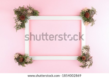 Festive elegant background. Blank photo frame on pastel pink background with fir tree twigs. Christmas, New Year, birthday concept. Flat lay, top view, copy space