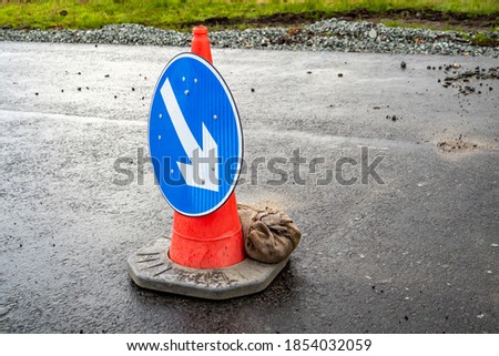 Traffic cones with white arrow on blue ground showing direction at roadworks.