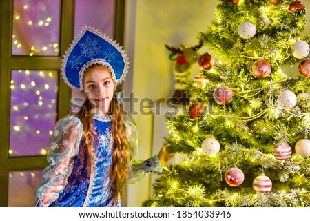 Little girl Snow Maiden near the New Year tree.