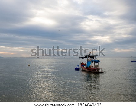 A local fishing boat floating at the seaside with beautiful sky in the evening. The sky in the background is colorful (blue, yellow, gold).