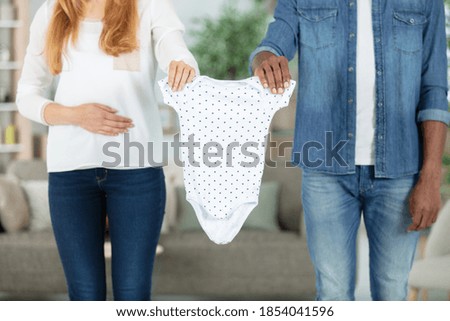 couple holding baby clothes together