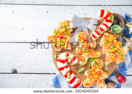 Christmas Pizza for child dinner, made with cookie cutters, in form of Christmas Traditional Symbols - Candy Cane, Gingerbread man, Xmas tree, funny food for New Year party 