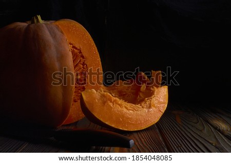 Raw, ripe, fresh, bright orange pumpkin squash on the dark background low key food photography for banner, blog, magazine, recipe, thanksgiving, Halloween