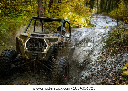 Side by side going through a large mudhole spraying mud and water everywhere  Royalty-Free Stock Photo #1854056725