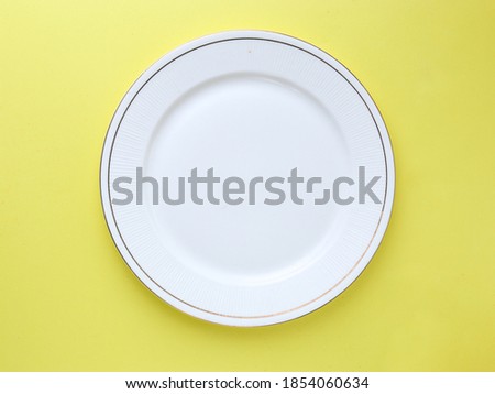 White plate on yellow background stock image.