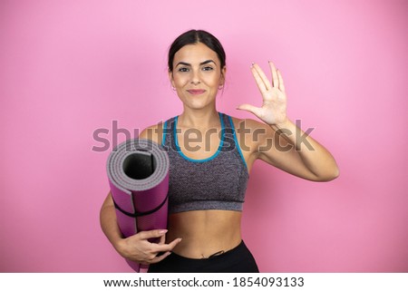 Young beautiful woman wearing sportswear over isolated pink background holding a splinter in her hand doing hand symbol