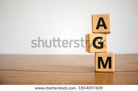 Wood cubes with acronym 'AGM' - 'annual general meeting' on a beautiful wooden table, white background. Business concept, copy space. Royalty-Free Stock Photo #1854097609