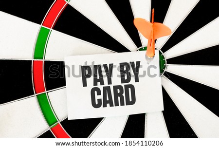 Handwriting pay by card on notepaper with dart arrow and dart board.