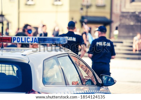Polish police intervention. Two officers are controlling a man withe the mask on the face. Police car in the front of the frame.