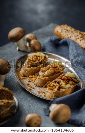 Still life picture of delicious and healthy bruschetta or sandwich with roasted garlic and champignon mushrooms on the blue, textured table
