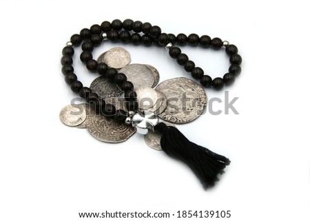 Antique silver coins and rosary on white background