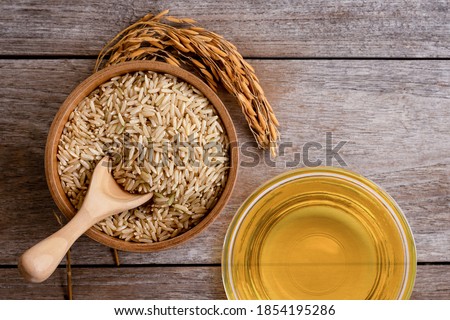 Rice bran oil extract with paddy and brown rice on wood table background. Top view. Flat lay. Royalty-Free Stock Photo #1854195286