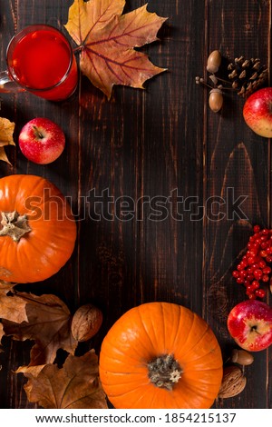 Orange pumpkins, fallen leaves, apples, nuts, berries, fruit tea on a wooden background. The concept of autumn template, Thanksgiving day. Copy space.