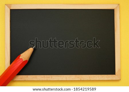 Red color pencil on the black chalkboard 