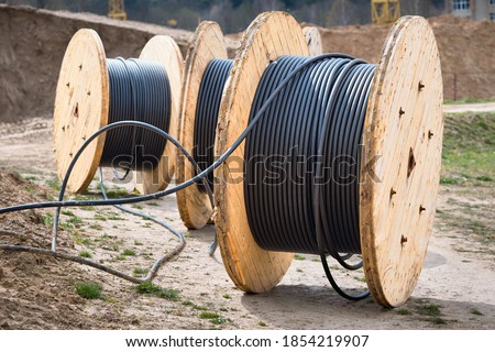 Concept of electricity supply for construction projects. Several wooden coils with power cable laid in trench.