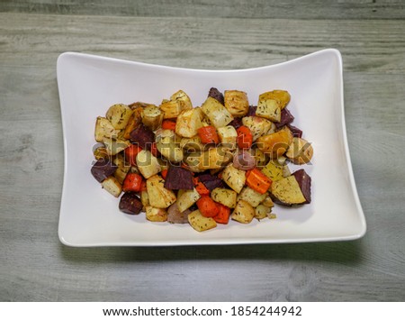 A white serving bowl with colorful roasted vegetables.