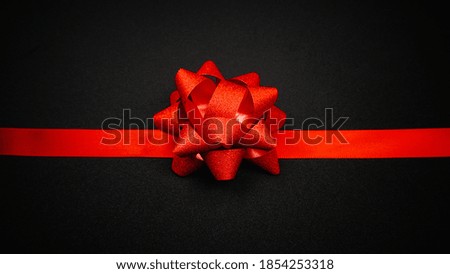 Red satin ribbon and sparkling star ribbon on black background