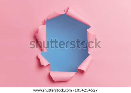 Torn ripped pink background with hole in center for your advertising content or promotion. Blank space to insert object. Absract horizontal shot. Breakthrough concept. Nobody at image. Through paper Royalty-Free Stock Photo #1854254527